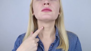 Tiroid hastalığı. Kadın tiroit bezinin bulunduğu boynunu işaret ediyor. Tiroid hormonlarının incelenmesi ve izlenmesi
