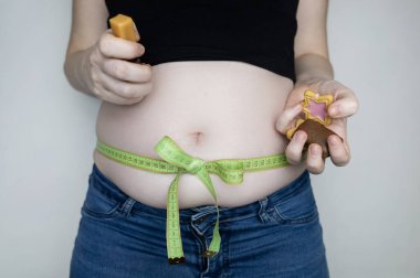 Obezite ve aşırı yemekten dolayı aşırı kilo. Büyük göbek, hediye olarak mezura ile bağlanmış. Şekerleme ve şekerden vücut yağları