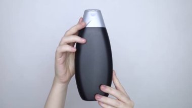 Bir kutu şampuanı elinde tutan kadın elleri, ne bir yazı ne de bir sembol var. Paketin yüzeyinde metin için boşluk aç. Hijyen ürününün altındaki siyah beyaz plastik kutu.