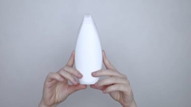 Bir kutu şampuanı elinde tutan kadın elleri, ne bir yazı ne de bir sembol var. Paketin yüzeyinde metin için boşluk aç. Hijyen ürününün altındaki siyah beyaz plastik kutu.