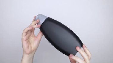 Bir kutu şampuanı elinde tutan kadın elleri, ne bir yazı ne de bir sembol var. Paketin yüzeyinde metin için boşluk aç. Hijyen ürününün altındaki siyah beyaz plastik kutu.