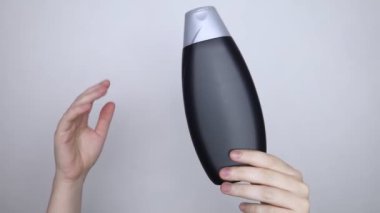Bir kutu şampuanı elinde tutan kadın elleri, ne bir yazı ne de bir sembol var. Paketin yüzeyinde metin için boşluk aç. Hijyen ürününün altındaki siyah beyaz plastik kutu.