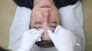 Yüz temizleme ve siyah başlık çıkarmadan geçen bir adam. Güzellik uzmanı komedi sökücü ya da uno ilmek kullanıyor. Güzellik salonunda profesyonel cilt bakımı