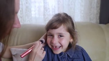 Anne kızının yüzüne makyaj yapıyor ve birlikte takılıyorlar. Ailedeki kadınlar arasındaki iletişim. Eğlence zamanı. Mutlu aile kavramı.