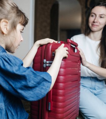 6 yaşındaki kızı bavul hazırlayan yorgun bir anne. Seyahat konsepti. Seyahat çantasına yakın çekim ve yolcuların yorgun yüzleri.