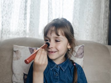 Anne kızının yüzüne makyaj yapıyor ve birlikte takılıyorlar. Ailedeki kadınlar arasındaki iletişim. Eğlence zamanı. Mutlu aile kavramı. Küçük kız makyajını yapıyor.