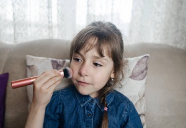Anne kızının yüzüne makyaj yapıyor ve birlikte takılıyorlar. Ailedeki kadınlar arasındaki iletişim. Eğlence zamanı. Mutlu aile kavramı. Küçük kız makyajını yapıyor.