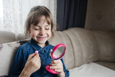 Anne kızının yüzüne makyaj yapıyor ve birlikte takılıyorlar. Ailedeki kadınlar arasındaki iletişim. Eğlence zamanı. Mutlu aile kavramı. Küçük kız makyajını yapıyor.