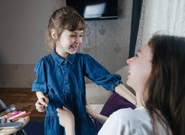 Kız, annesinin yüzüne makyaj yapar ve oynaşır. Bakıcı ebeveyn çocuğunun yüzünü boyamasına izin verir. Mutlu bir çocukluk. Sevgi dolu bir aile ve eğlence anlayışı. Küçük kız makyajını yapıyor.