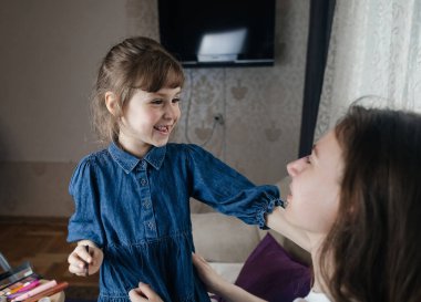 Kız, annesinin yüzüne makyaj yapar ve oynaşır. Bakıcı ebeveyn çocuğunun yüzünü boyamasına izin verir. Mutlu bir çocukluk. Sevgi dolu bir aile ve eğlence anlayışı. Küçük kız makyajını yapıyor.
