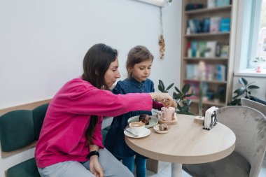 Anne ve kızı bir kafede, kahve ve kakao içiyor, kruvasan ve kek yiyor. Eğleniyoruz ve birlikte vakit geçiriyoruz.