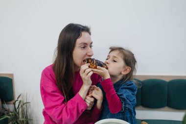 Anne ve kızı bir kafede, kahve ve kakao içiyor, kruvasan ve kek yiyor. Eğleniyoruz ve birlikte vakit geçiriyoruz.
