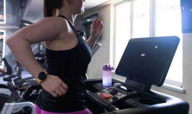 Spor salonunda koşu bandında çalışan normal vücutlu gerçek bir kadın. Gerçekçi zindelik ve sağlıklı kilo verme motivasyonu