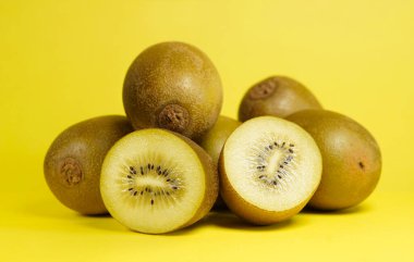 Sarı arka planda dilimlenmiş kiwifruit ile ön manzara portresi yakın Kiwi altın meyvesi.