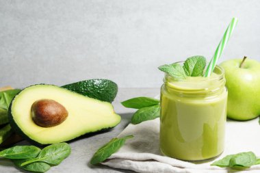 Avokado ıspanağı ve yeşil elma suyu. Sağlıklı tropikal içecekler. Nane yaprakları ve dilimlenmiş avokado meyvesi, elma ve ıspanak yapraklarıyla dolu cam kavanozun önü..