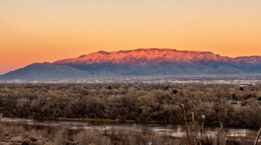 Albuquerque, New Mexico at sunset with Rio Grande in the front and the Sandia Mountains in the background. clipart