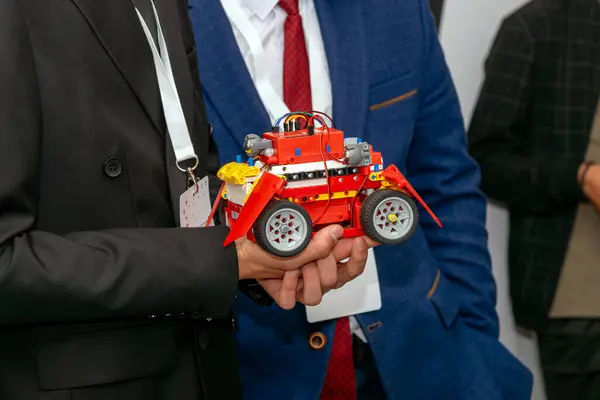 Öğrencinin elleri, yarışmada robotu tutuyor.