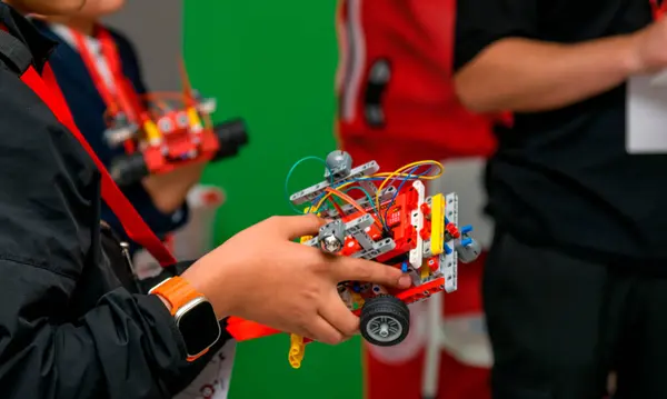 Asyalı bir çocuk monte edilmiş robotunu elinde tutuyor.