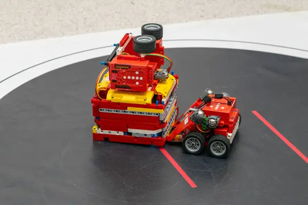 Küçük kırmızı bir robot ringde büyük bir robotla dövüşüyor.