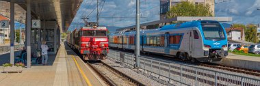 Celje, Slovenya - Ekim 03, 2022: Slovenya Demiryolları Elektrik kamu kırmızı ve mavi nakliye treni bir tren istasyonunda duruyor.