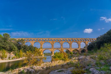 Gardon nehrinin üç katlı turuncu kireçtaşı Pont du Gard su kemeri manzaralı. Kaynak