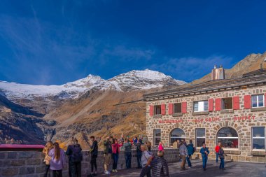 ALP GRUEM, SWITZERLAND - OCTOBER 28,2022: People at the Bernina Express station of Rhaetian railway on a autumn day at Alp Gruem clipart