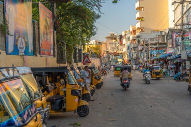 Puttaparthi, Andhra Pradesh, India - January 18, 2023: Yellow rickshaw taxis on a road in Puttaparthi village.