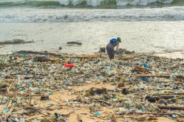 Jimbaran Sahili, Endonezya - 13 Şubat 2023 Bali 'de Jimbaran Sahili çöplerle dolu, çöpte kullanılacak şeyleri arayan bir insan