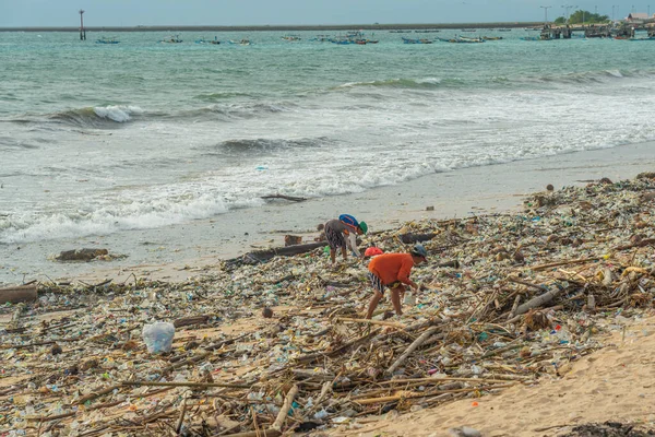 stock image Jimbaran Beach, Indonasia - February 13.2023: Jimbaran beach on Bali full of garbage at the sandy beach, a person search things to use in garbage