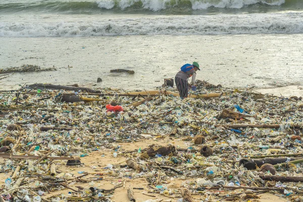 stock image Jimbaran Beach, Indonasia - February 13.2023: Jimbaran beach on Bali full of garbage at the sandy beach, a person search things to use in garbage