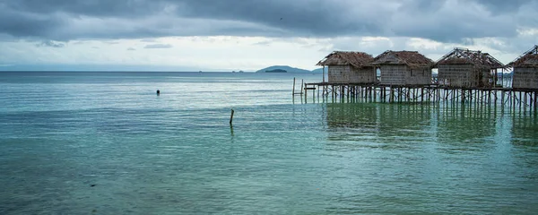 Old destroyed water houses on the coast of the village of Saporkren Waisai, Raja Ampat, background cloudy sky