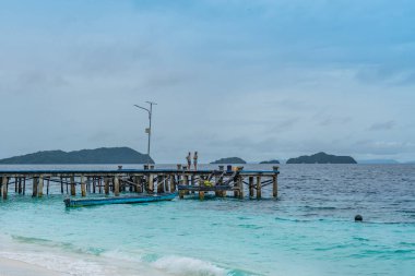 Raja Ampat, Batı Papua, Endonezya, Şubat 06.2023: Ahşap iskele ve turkuaz deniz insanları