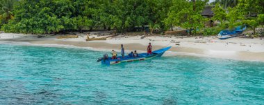 Raja Ampat, Batı Papua, Endonezya, Şubat 06.2023: Fam Adası, Raja Ampat 'ta uzun bir tekne ve turkuaz denizindeki insanlar