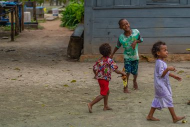 Raja Ampat, Batı Papua, Endonezya, Şubat 06.2023: Raja Ampat 'ta oynayan yerli papualı çocuklar, arka planda mavi bir ev