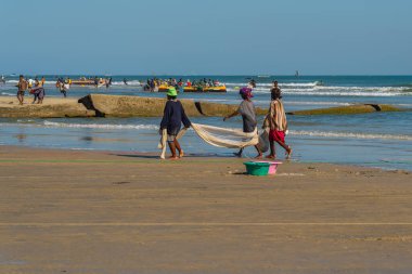 Morondava, Madagascar - May 31.2023: Three women at the coastline from Morondava walking with a fishnet