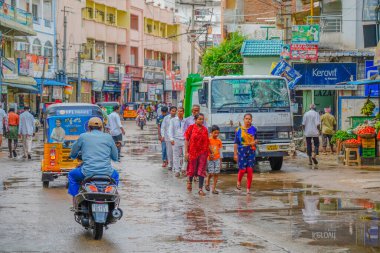 Puttaparthi sokaklarında insanlar triportör, scooter ve arabayla