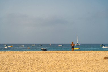 Cape Verde Adası 'ndaki Santa Maria sahilinde mavi gökyüzü olan bir kadının arka görüntüsü.