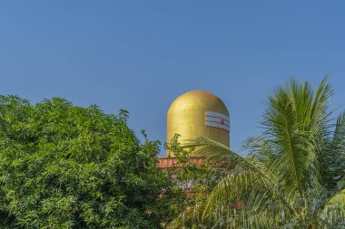 Hindistan, Puttaparthi 'deki altın rengi Lord Shiva Lingam tapınağının tepesinde yeşil ağaçlar var.