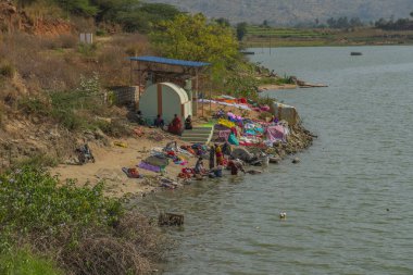 Puttaparthi, Hindistan - 10 Aralık 2023: Kadınlar renkli sarileri yıkıyor ve Puttaparthi 'de bir gölde kapanıyor