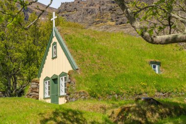 Historic turf Church Hofskirkja in the small village of Hof, Iceland. Hofskirkja Hof, scene with turf roof church in old Iceland traditional style clipart