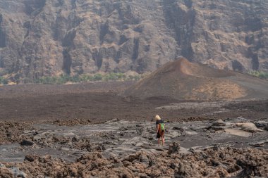 Pico do Fogo 'da, Cape Verde' deki Cha das Caldeiras köyündeki lav tarlasında bir kadının arka görüntüsü.