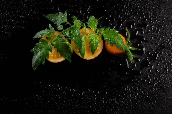 Nasse Gelbe Tomaten Mit Blättern Auf Schwarzem Hintergrund — Stockfoto