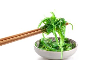 Çubuklarda Japon yosun salatası var. Japon mutfağı - Wakame salatası, beyaz arka planda izole edilmiş Chuka yosun salatası. 