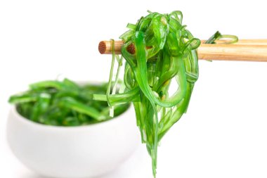 Çubuklarda Japon yosun salatası var. Japon mutfağı - Wakame salatası, beyaz arka planda izole edilmiş Chuka yosun salatası.