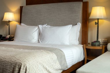 Masa lambası yatak odasında beyaz yatak örtüsüyle yatağın yanında.