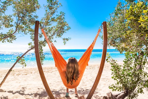View from behind of a beautiful woman relaxing in a unique hammock with a spectacular view of the Caribbean ocean. Relaxing and enjoying nature\'s beauty