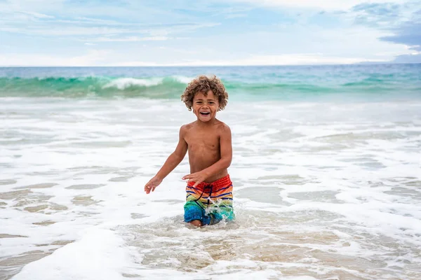 笑着年轻的非洲裔美国男孩在海滩上跑来跑去 在一个家庭度假 在海浪中玩 玩得开心又活跃 — 图库照片