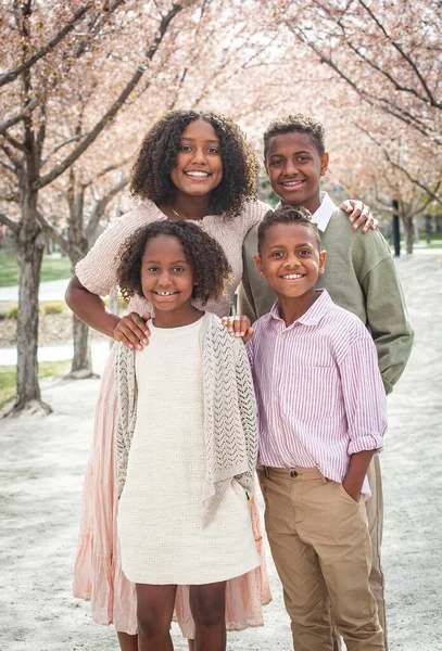 一个美丽的一群不同的孩子站在一排樱花树上的画像 笑非裔美国兄弟姐妹在一起摆姿势 不同的家庭概念 — 图库照片