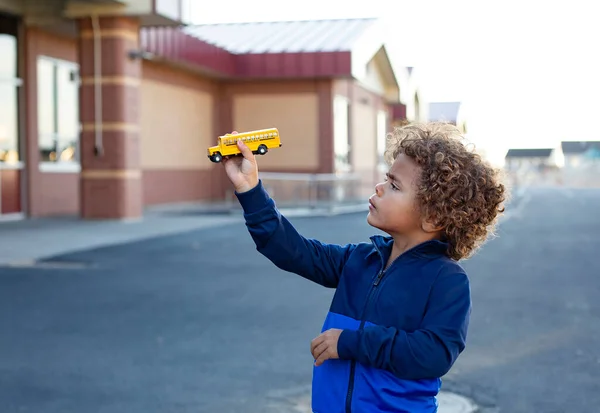 Netter Kleiner Afroamerikanischer Junge Der Mit Einem Spielzeugschulbus Auf Einem Stockbild