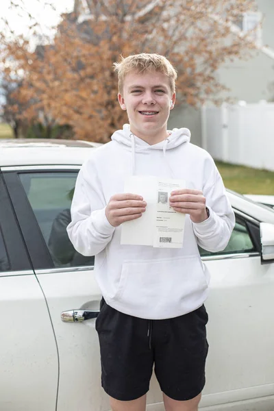 彼の運転免許証を保持しているスマイルな白人十代の少年 ストック写真
